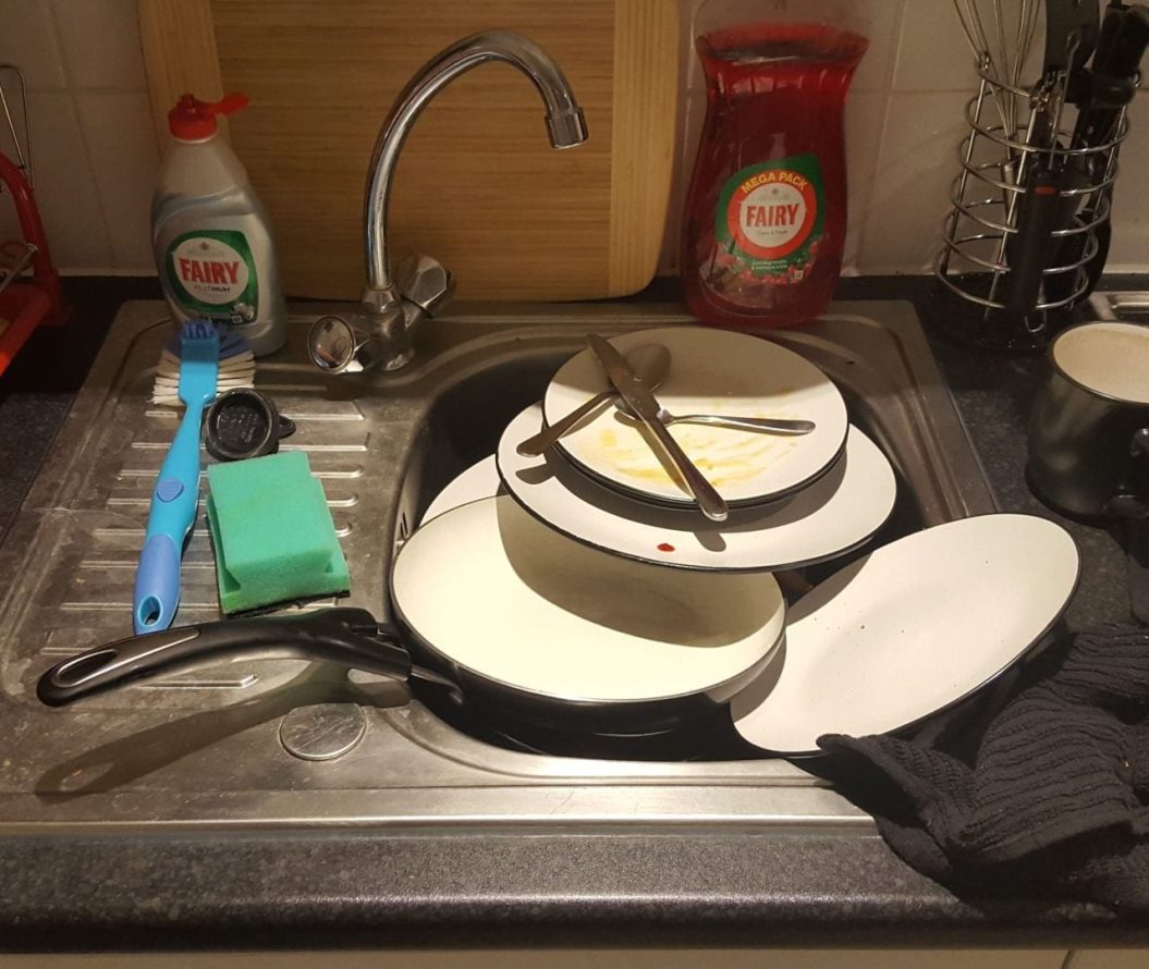 Pile of dirty plates in a sink.