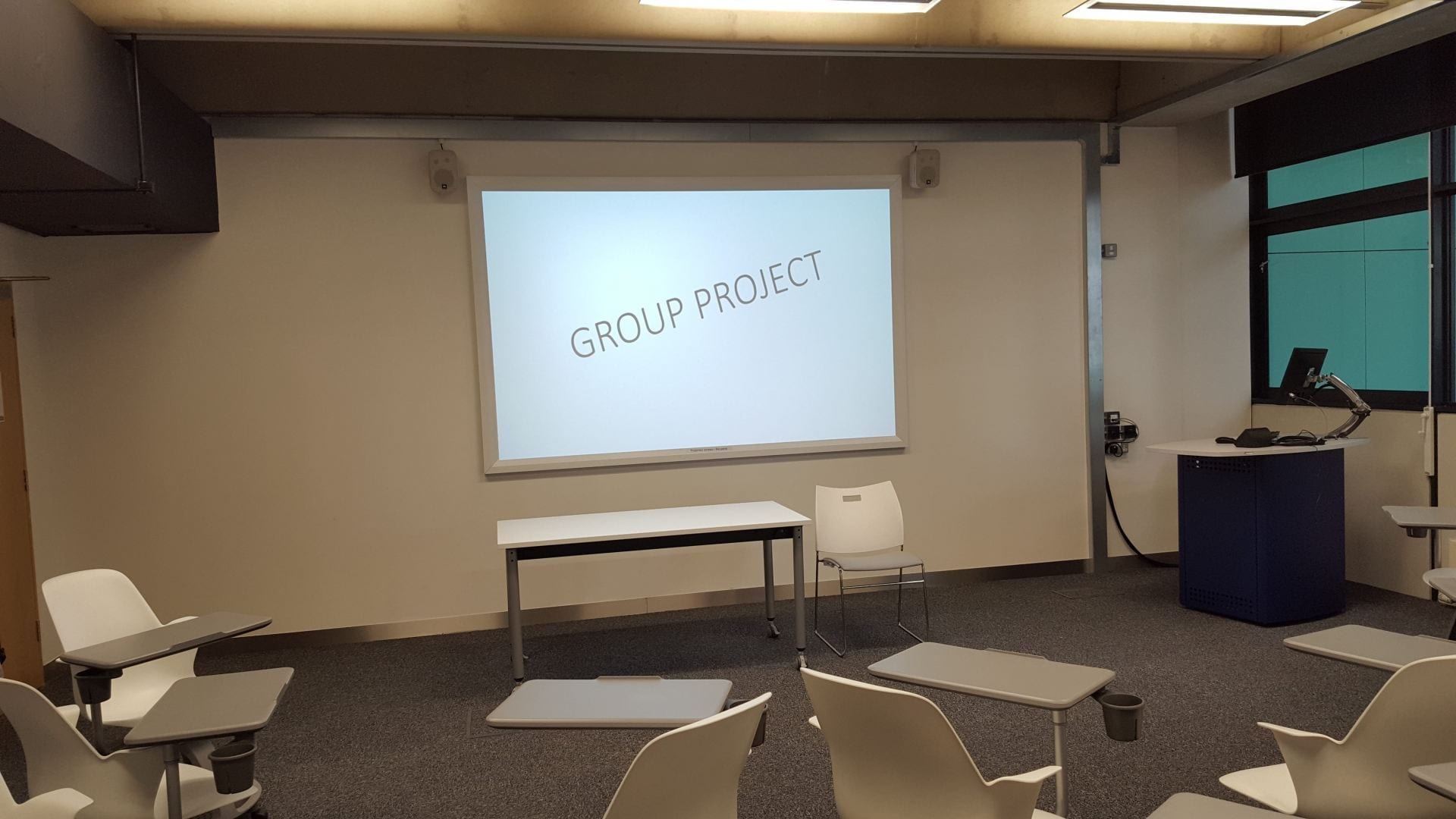 Large white board displaying Group Project in empty class room.