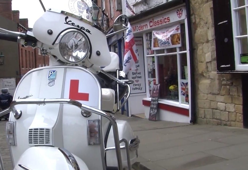White vespa with Learner plates, parked in front of Modern Classics shop front.