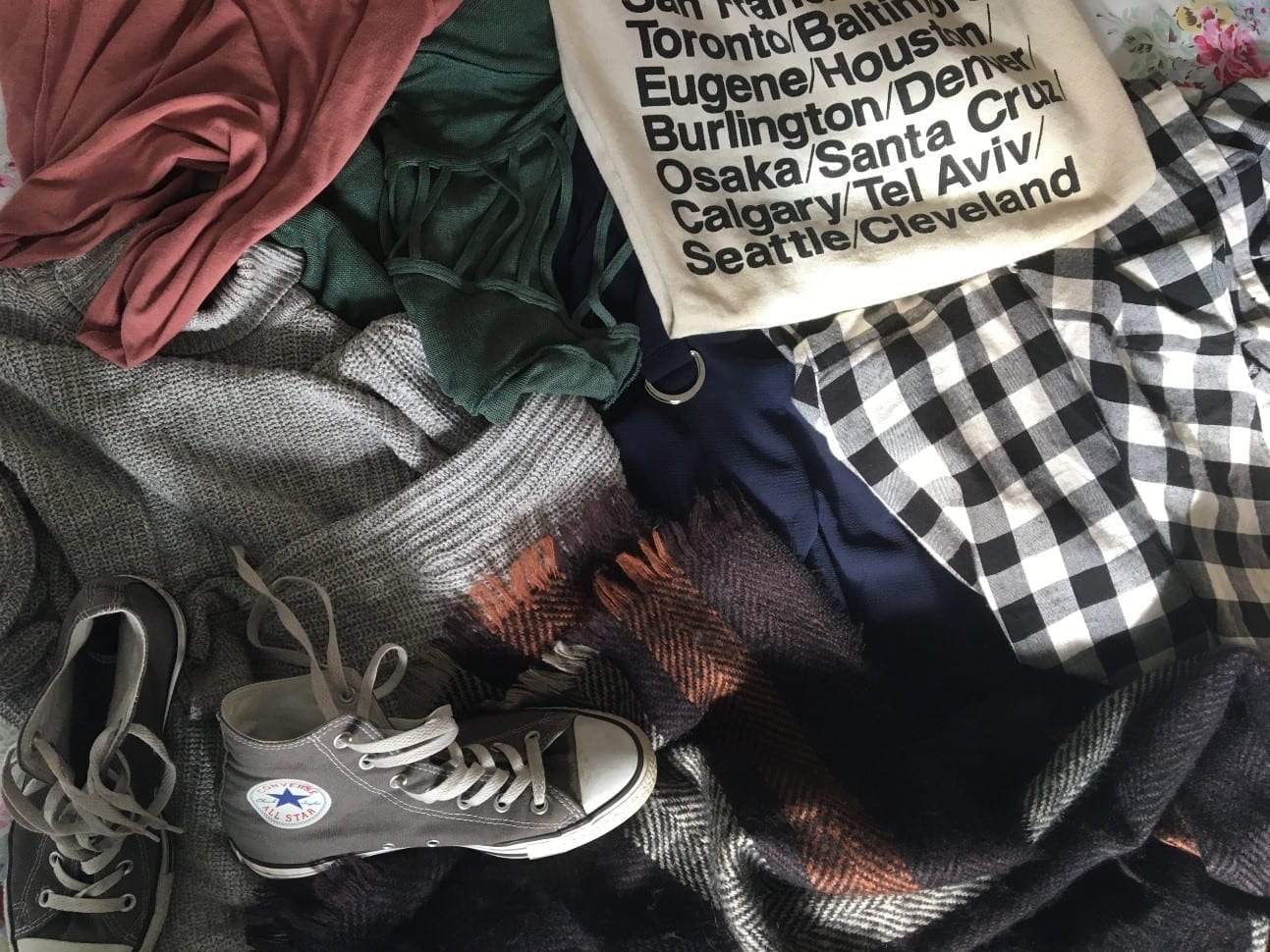 Pile of clothes, tote-bag and converse shoes.