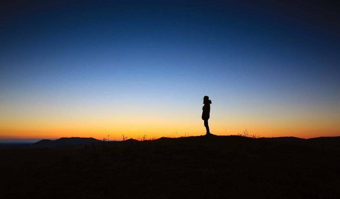 Silhouette of a man on a horizon at sunrise.