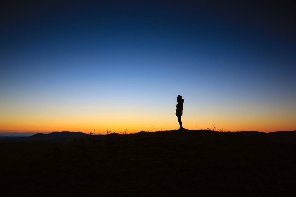 Silhouette of a man on a horizon at sunrise.