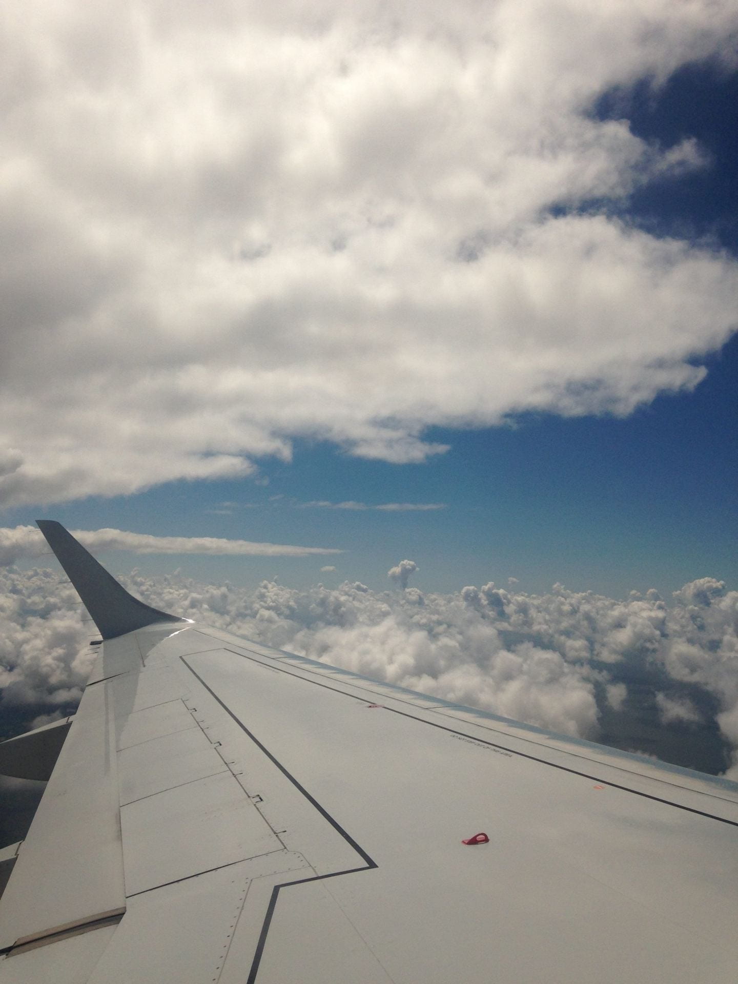 View from an aeroplane window, of the wing, above the clouds.
