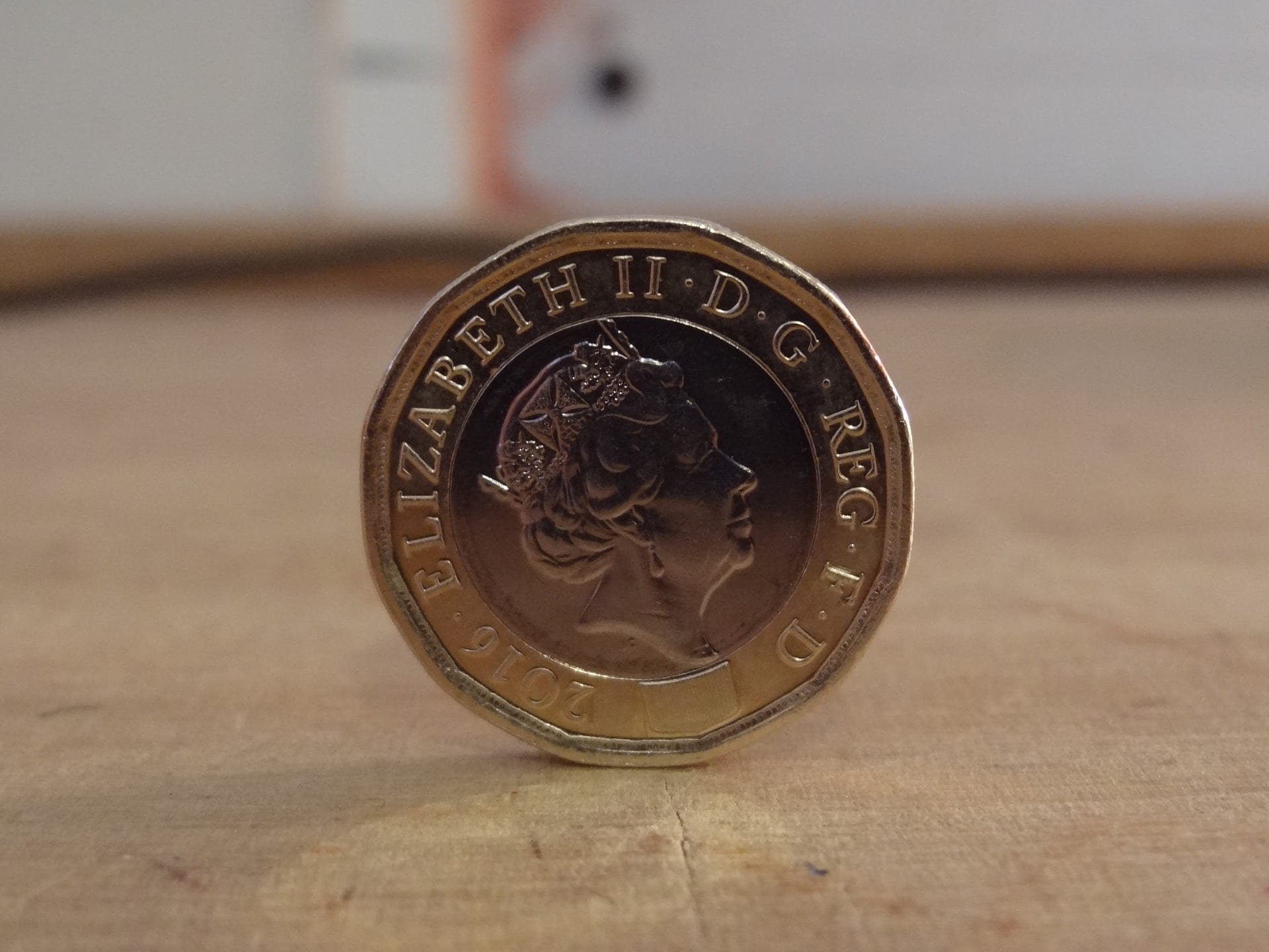 Back of a one pound coin, stood up on a table.