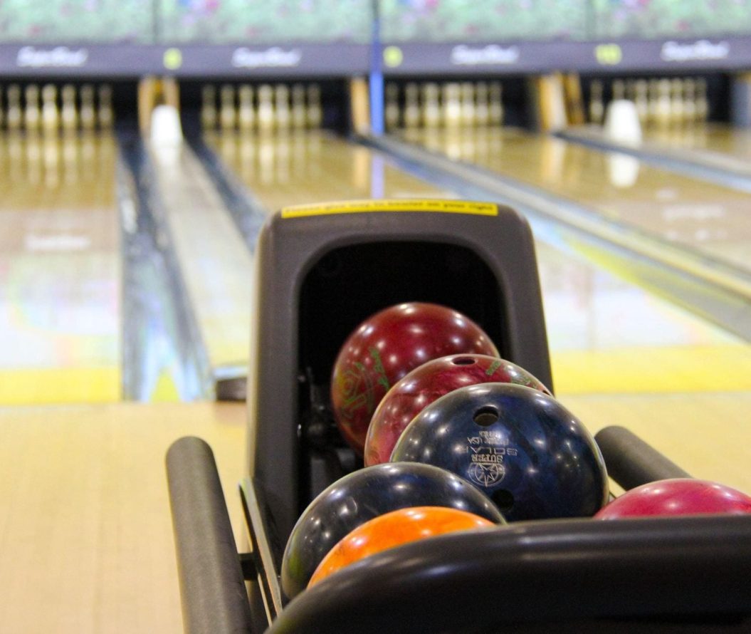 Bowling balls, in front of a row of bowling lanes.