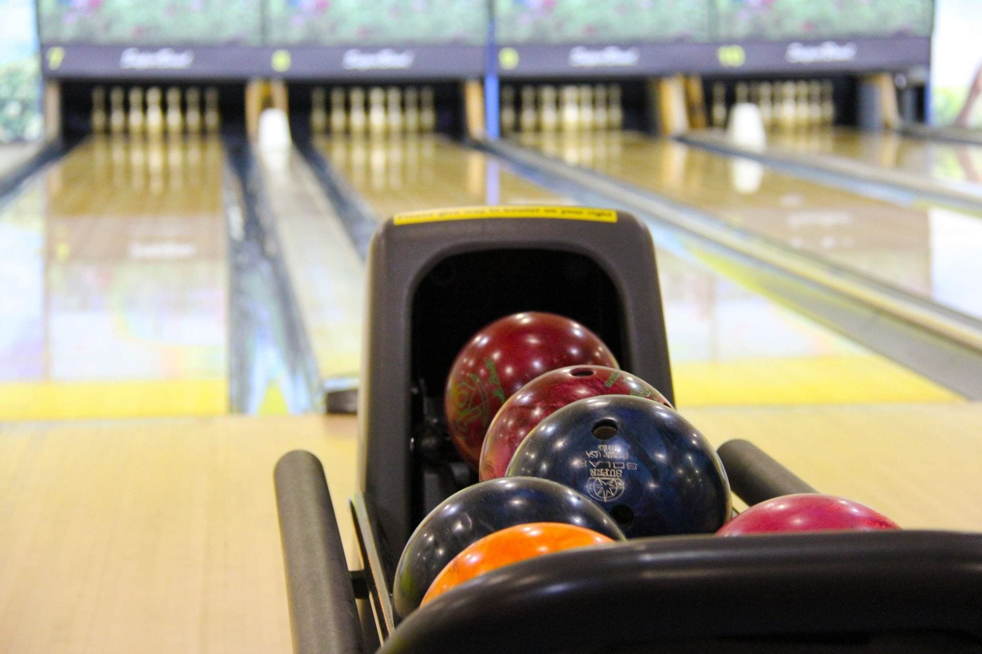 Bowling balls, in front of a row of bowling lanes.