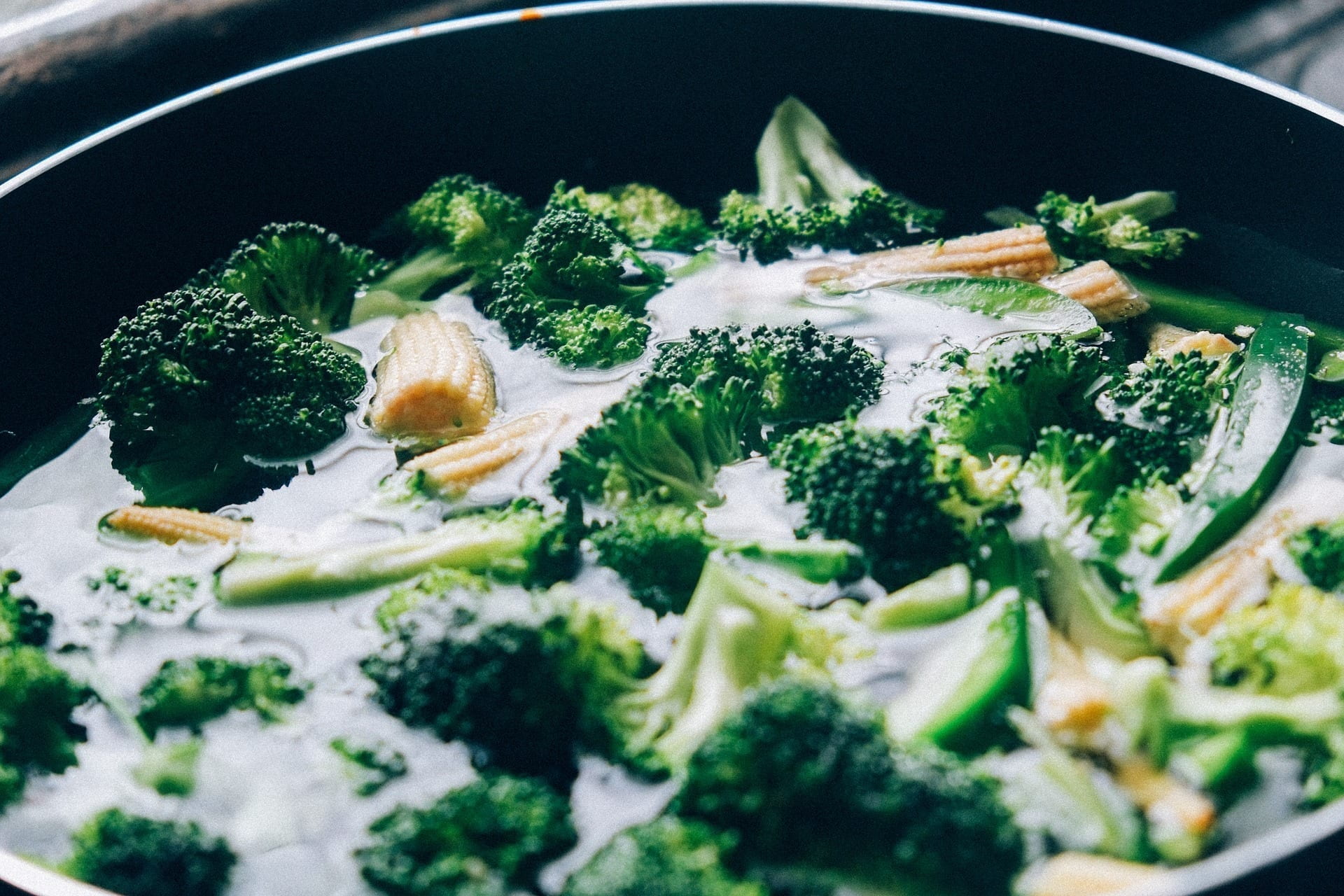 Broccoli, sweetcorn and snap peas, in a pan of water.
