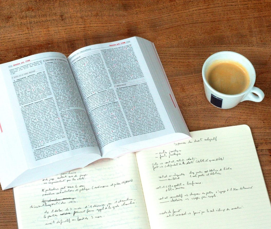 Open text book, notebook and a cup of coffee.