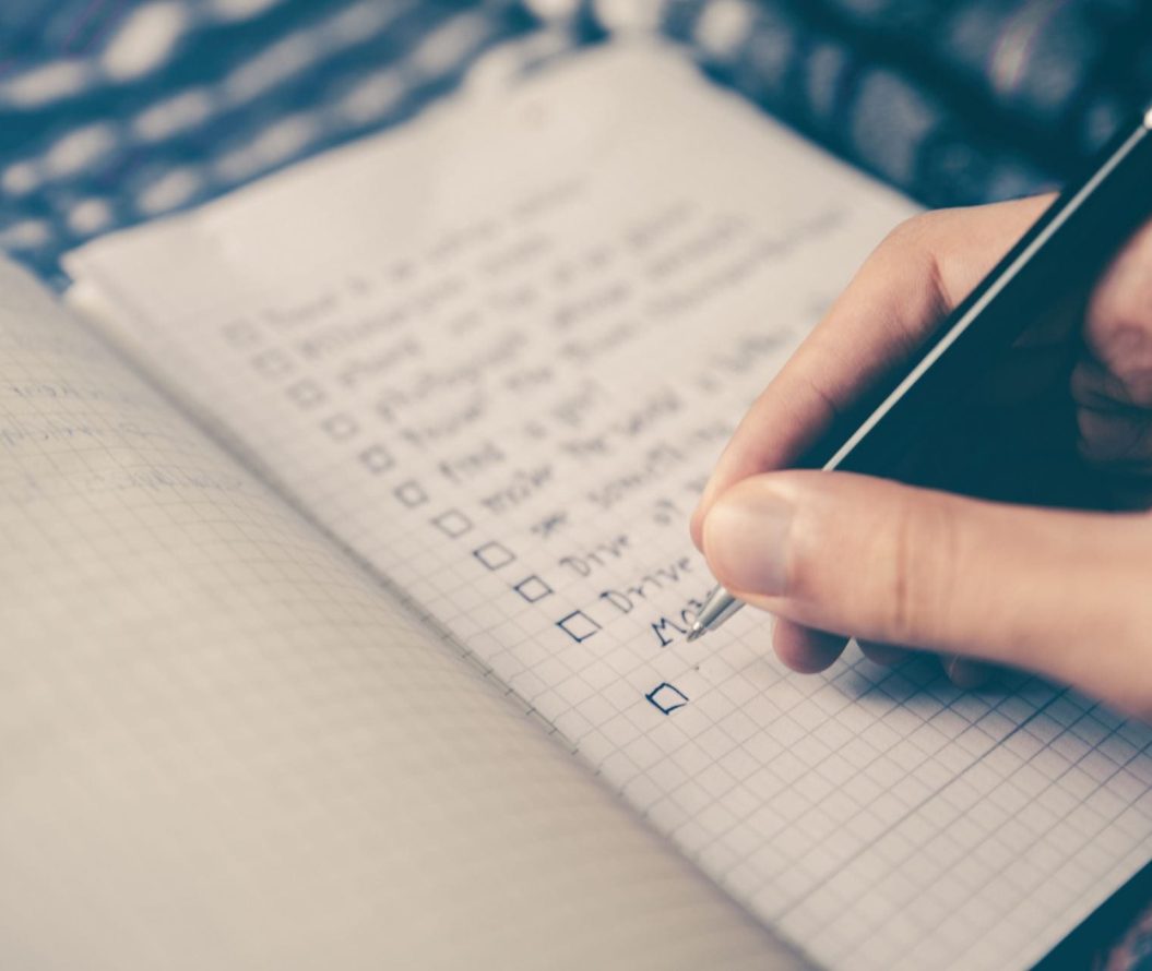 Somebody creates a checklist on grid paper with a pen