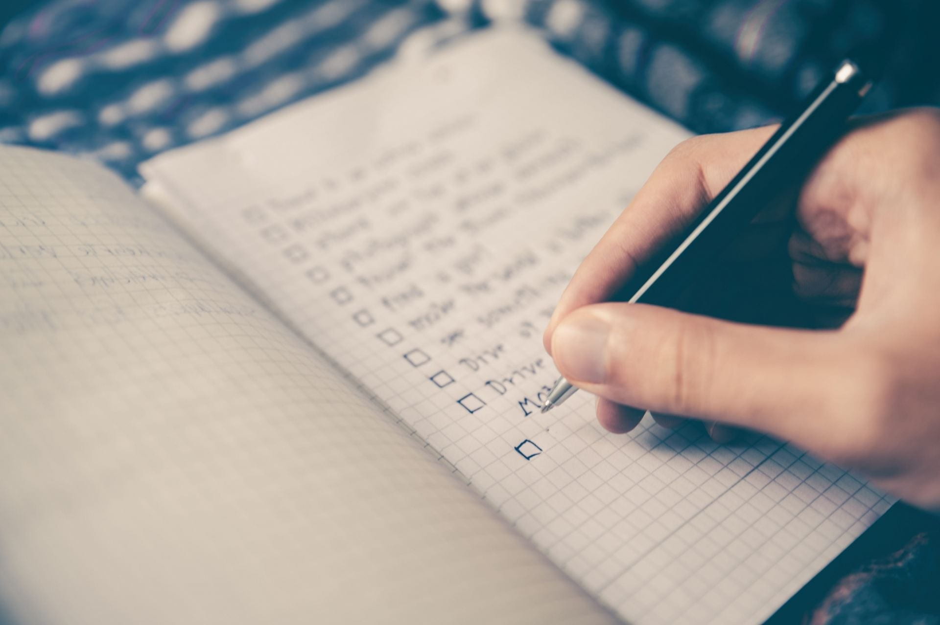 Somebody creates a checklist on grid paper with a pen
