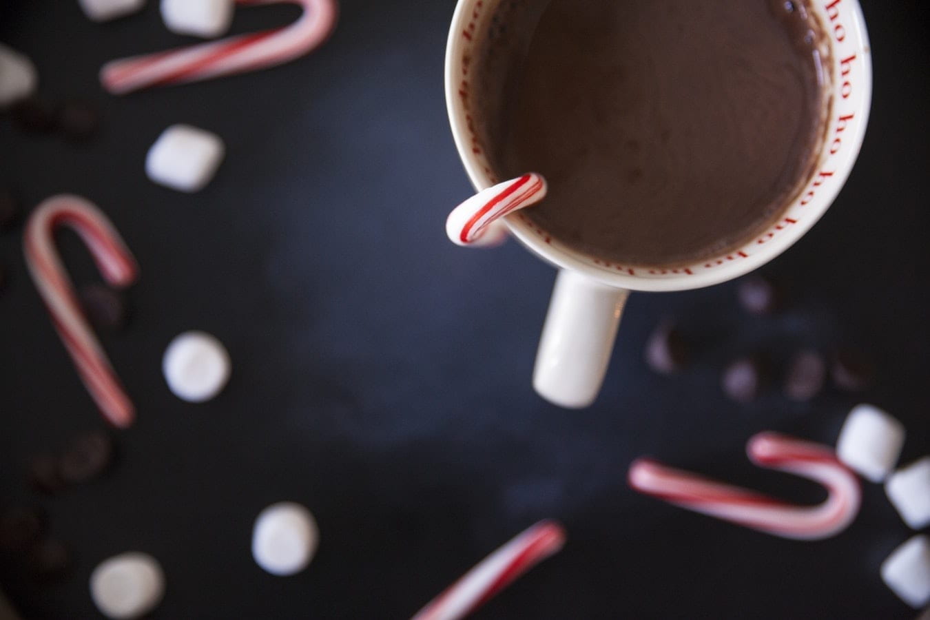 Hot chocolate in a mug surrounded by marshmallows and candy canes