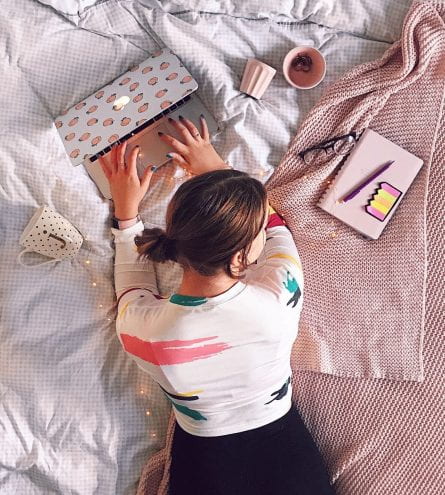 Top down photo of a young woman studying on her bed