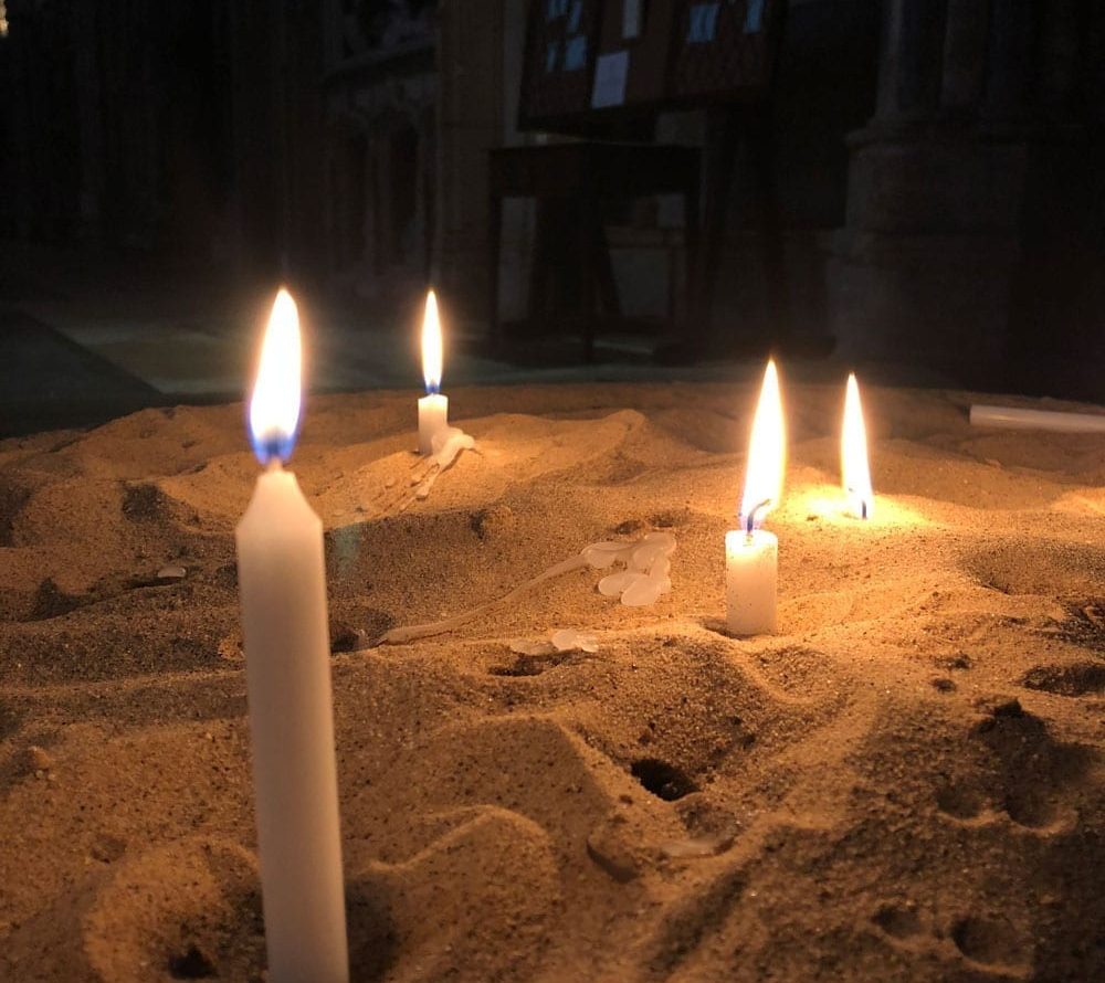 Lit candles placed in sand in Lincoln Cathedral