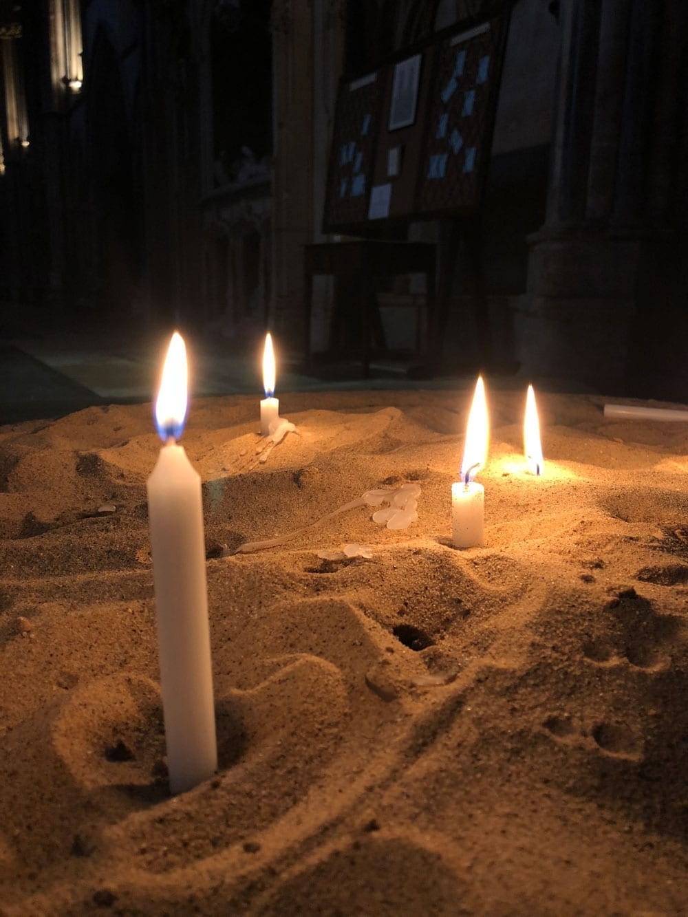 Lit candles placed in sand in Lincoln Cathedral
