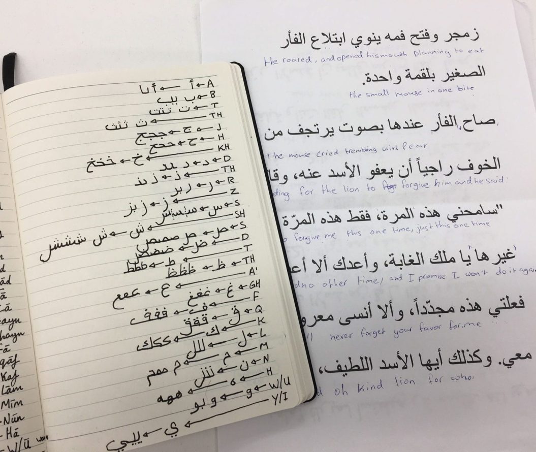 A notebook and a sheet of paper with writing in Aarabic