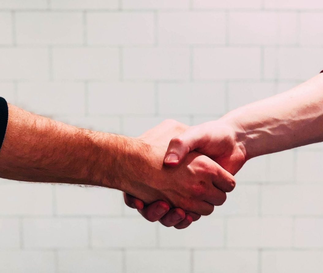Two men shaking hands in front of a white wall
