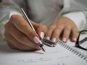 Woman's hand holding a pen to paper