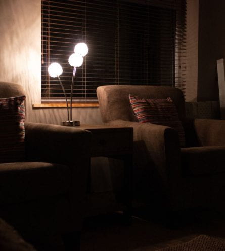 dim lit room with two armchairs with pillows on them