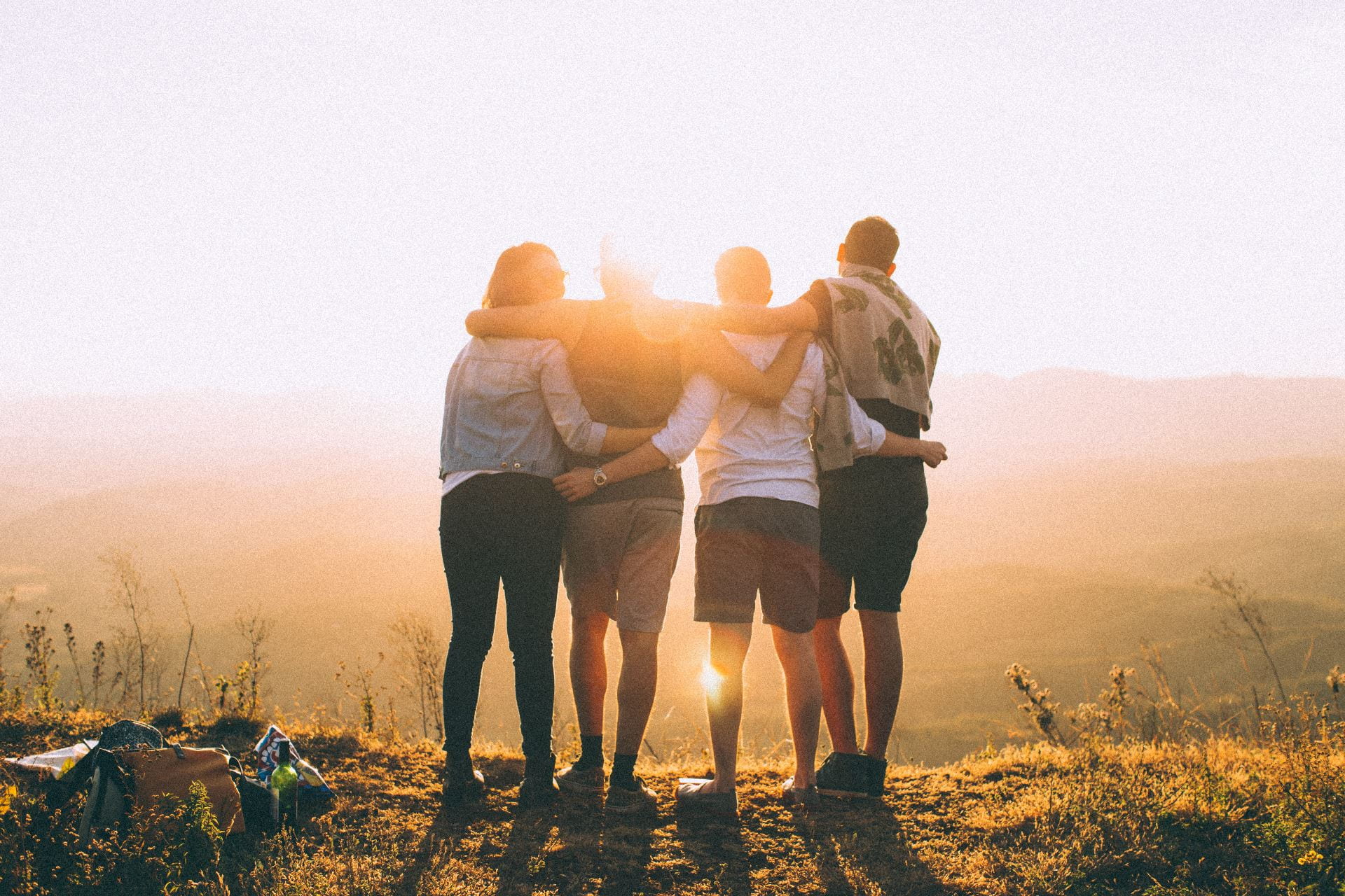 Four people linking arms looking at sunset.