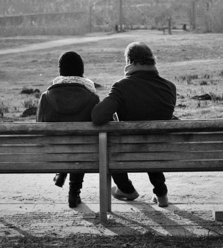 two people sat on a bench in a park, black and white