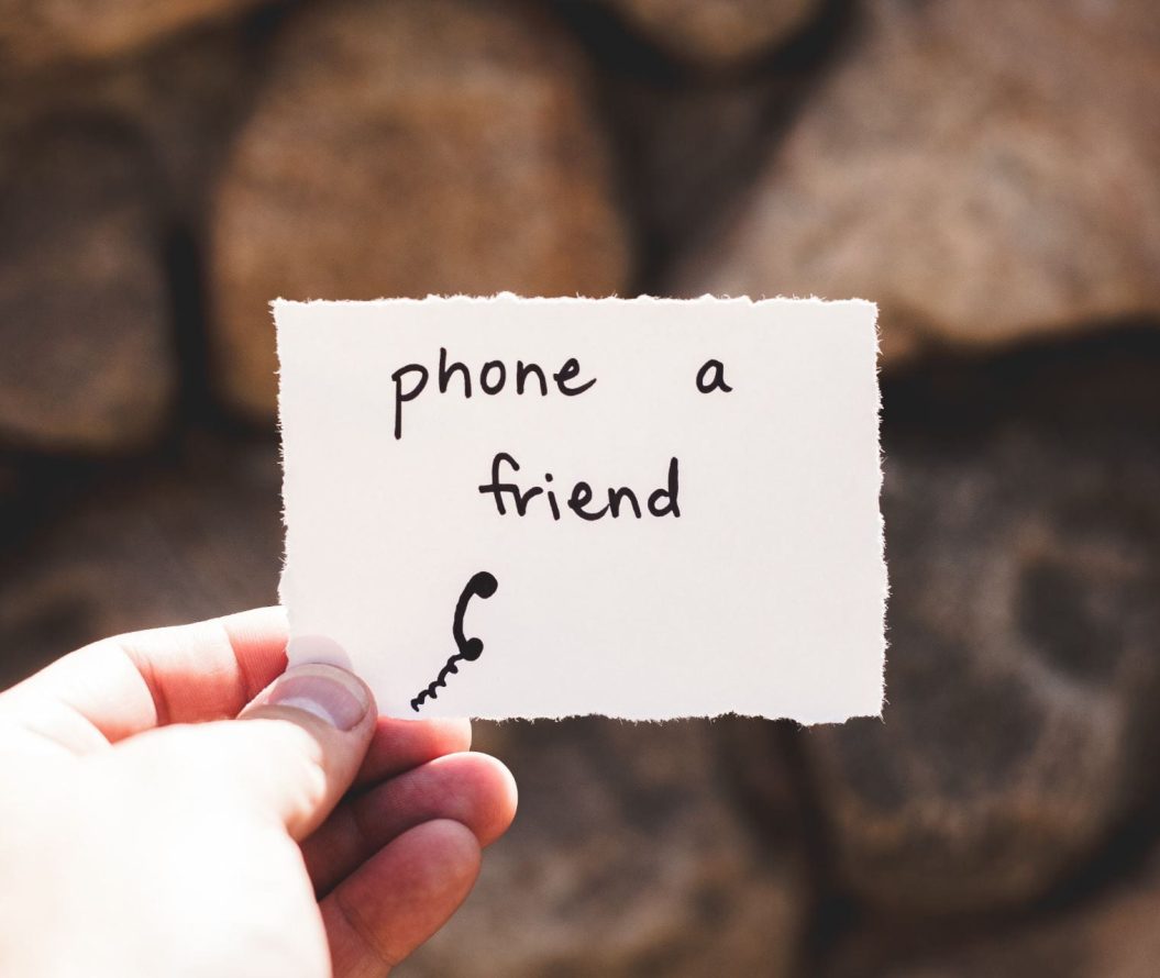 person holding a piece of paper with 'phone a friend' written on it