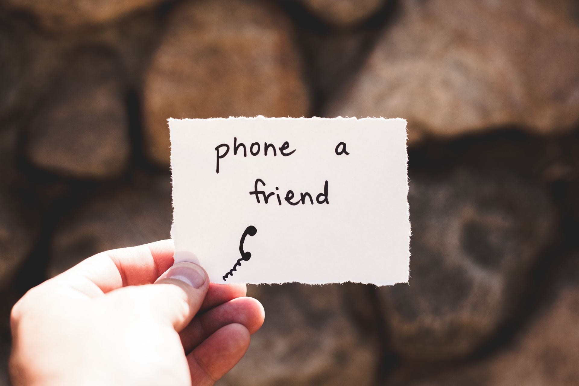 person holding a piece of paper with 'phone a friend' written on it