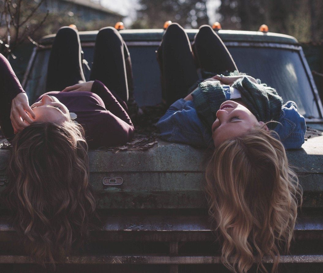 two girls on a rusty car smiling