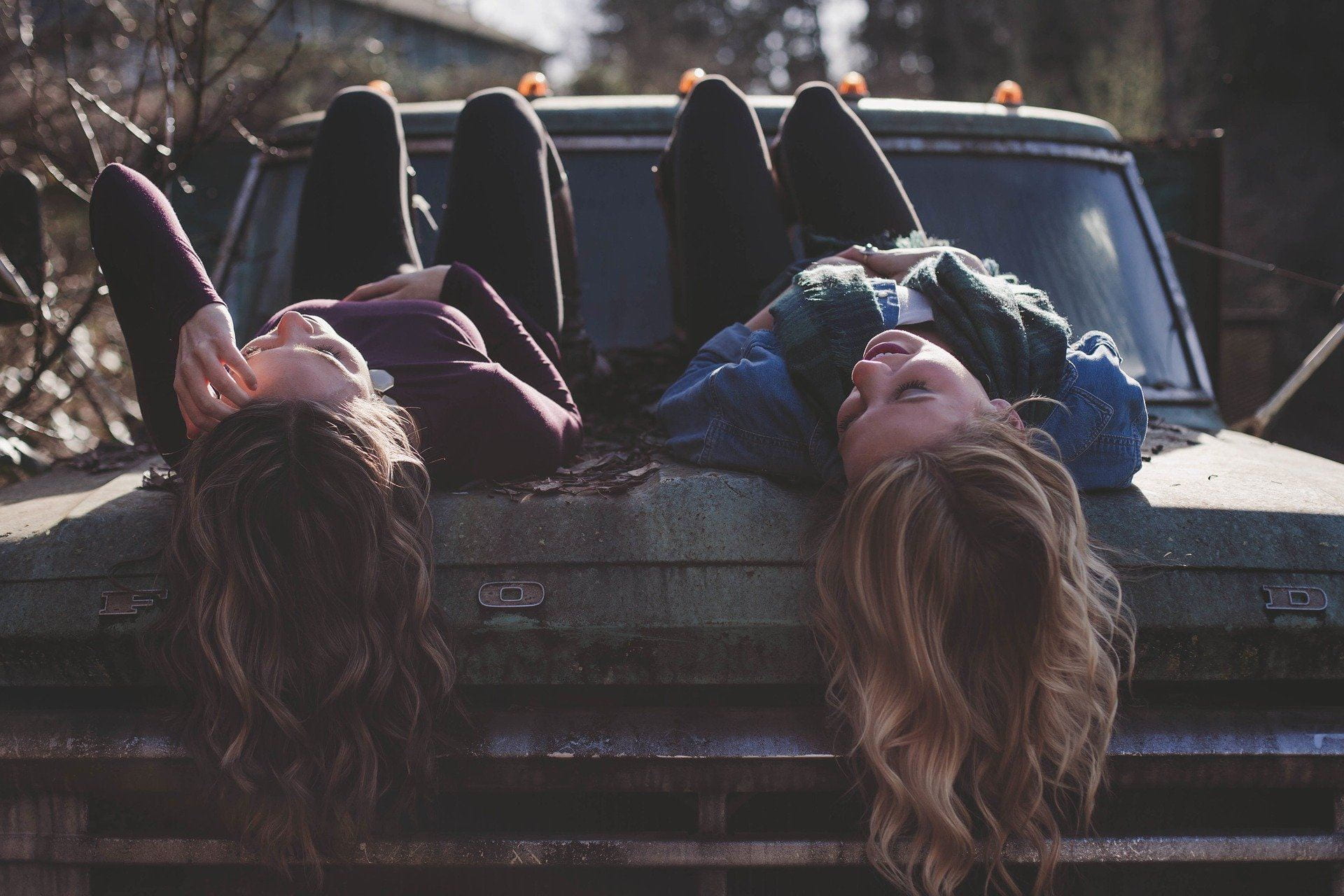 two girls on a rusty car smiling