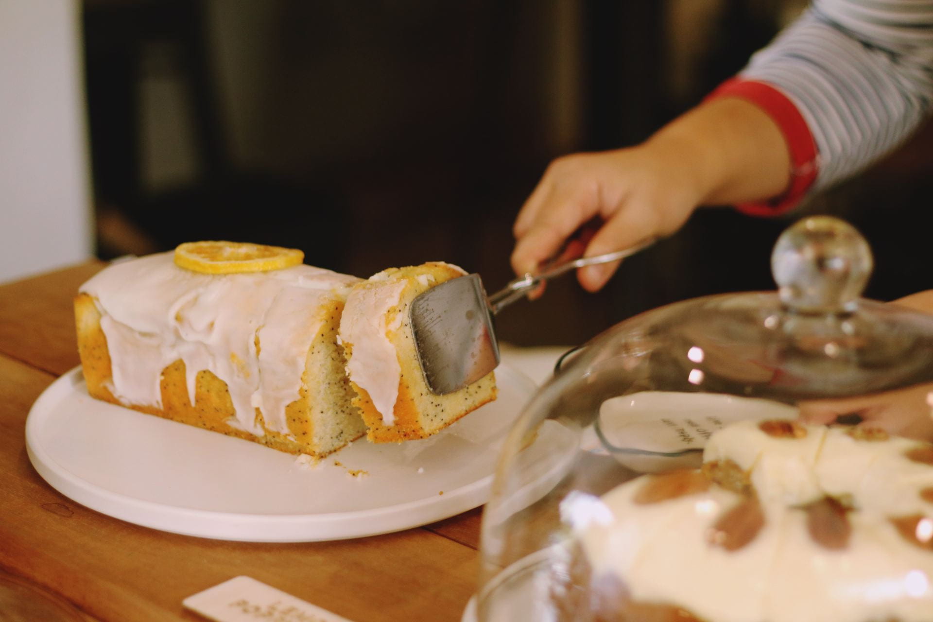 A person picking up a slice of lemon cake