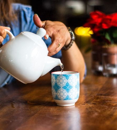 A lady pouring tea from a teapot into a mug