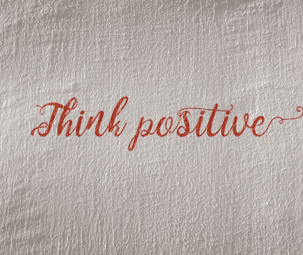 Piece of paper that reads think positive, in red pen