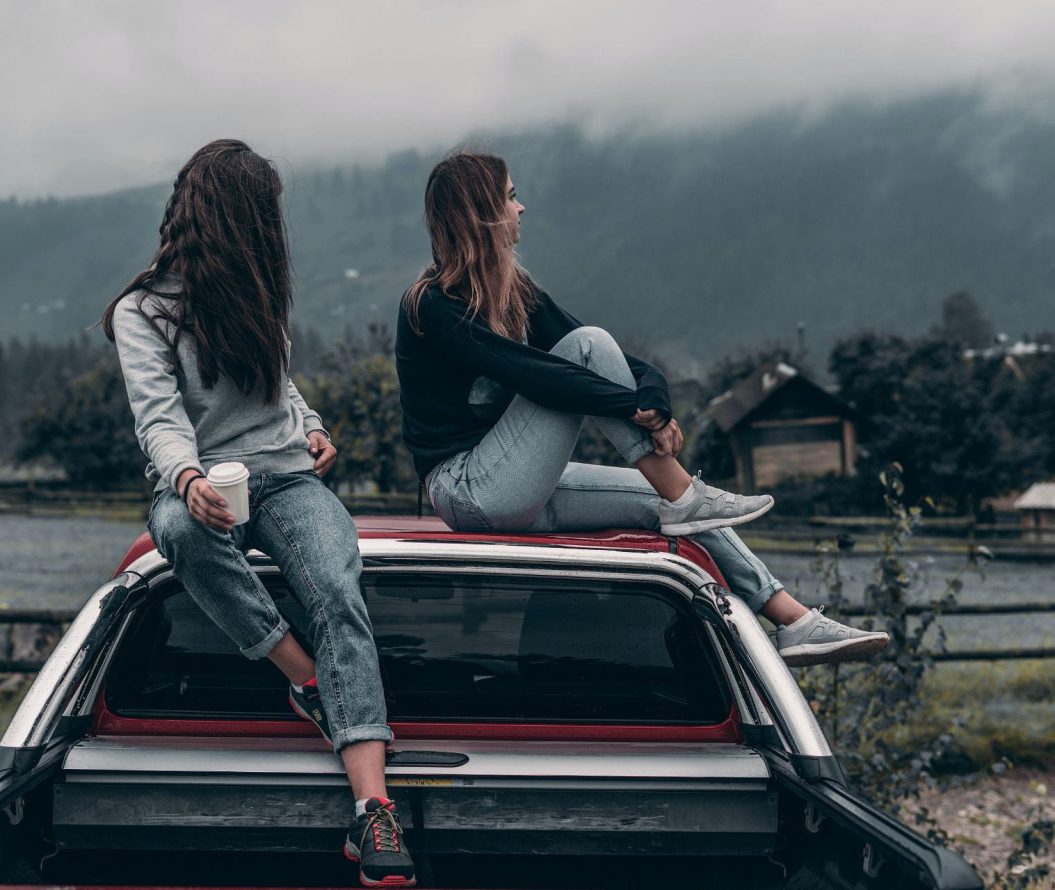 Two women sitting on car roof