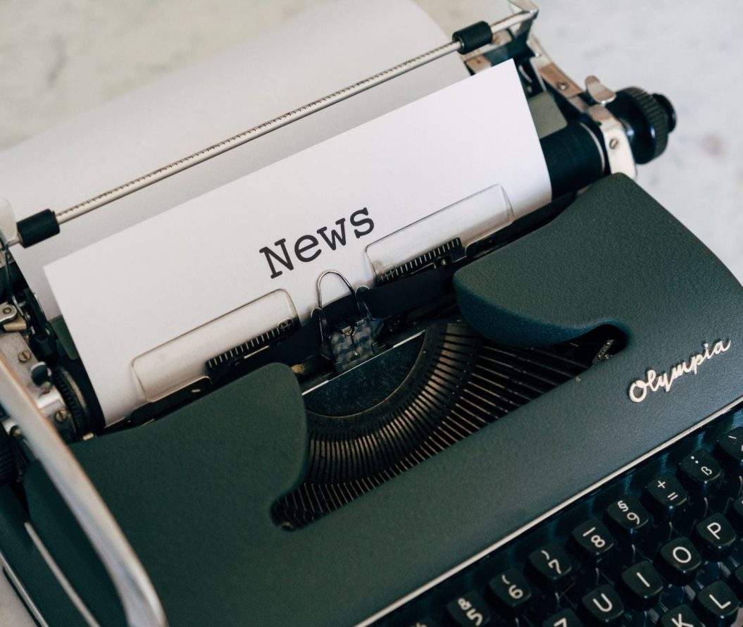 Typewriter displaying a piece of paper saying "news".