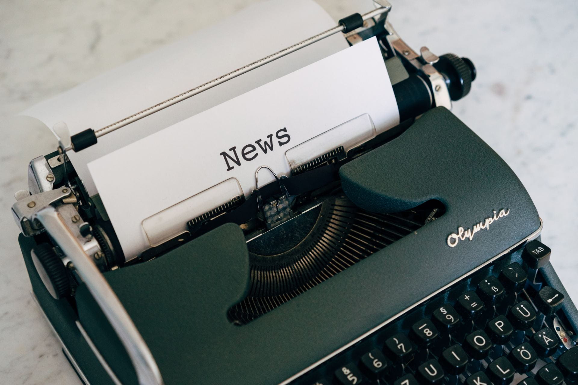 Typewriter displaying a piece of paper saying "news".