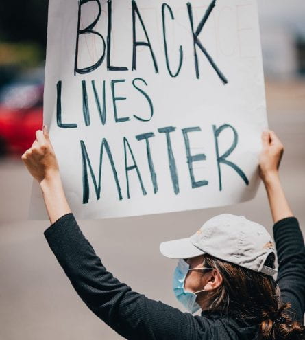 Girl with a hat on holding Black Lives Matter banner