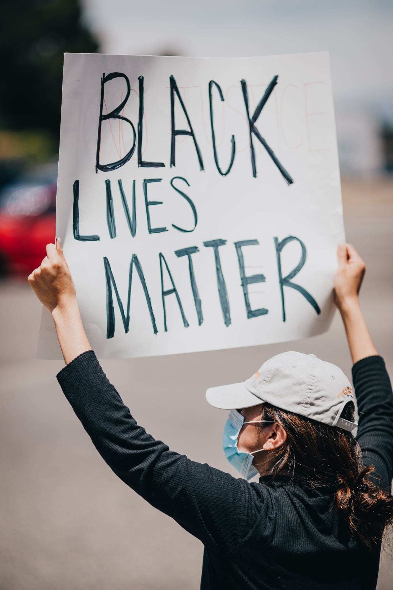 Girl with a hat on holding Black Lives Matter banner