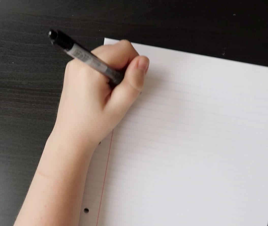 A person about to write on a piece of paper