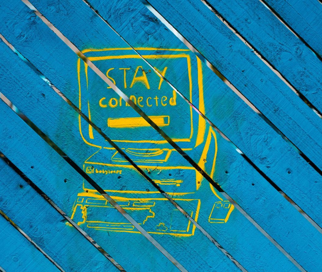 Yellow graffiti of a computer, that reads "stay connected"