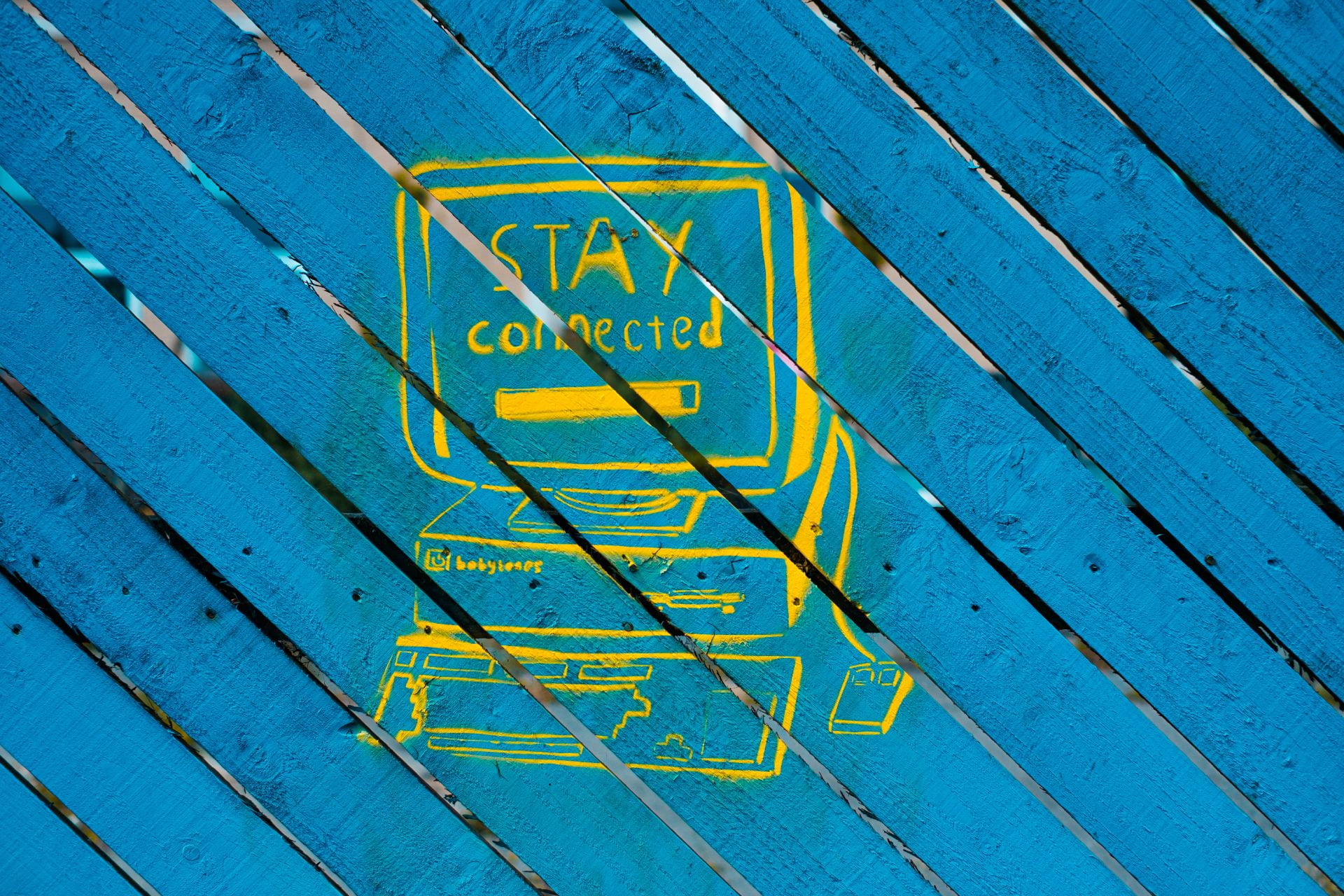 Yellow graffiti of a computer, that reads "stay connected"