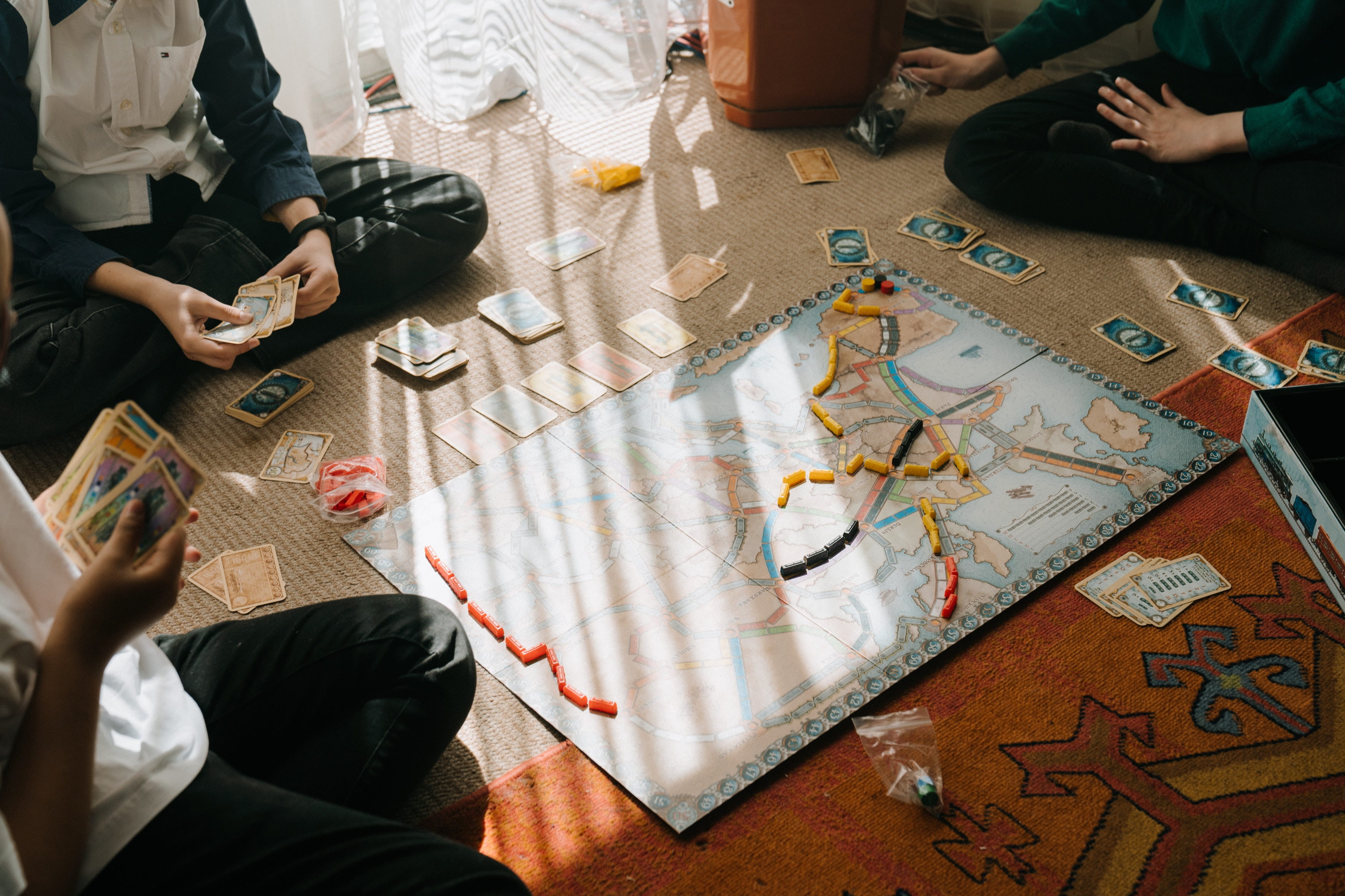 Group of people sitting on floor around a board game