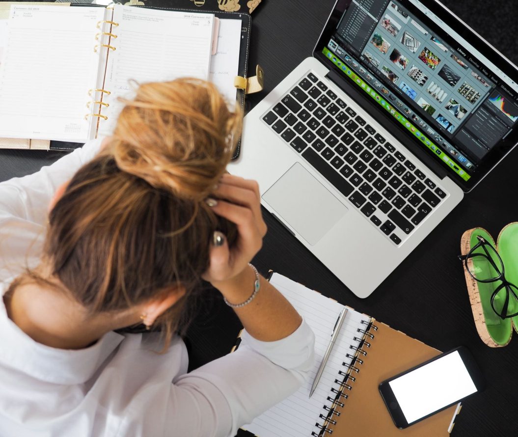 A woman stressed at her desk facing her laptop