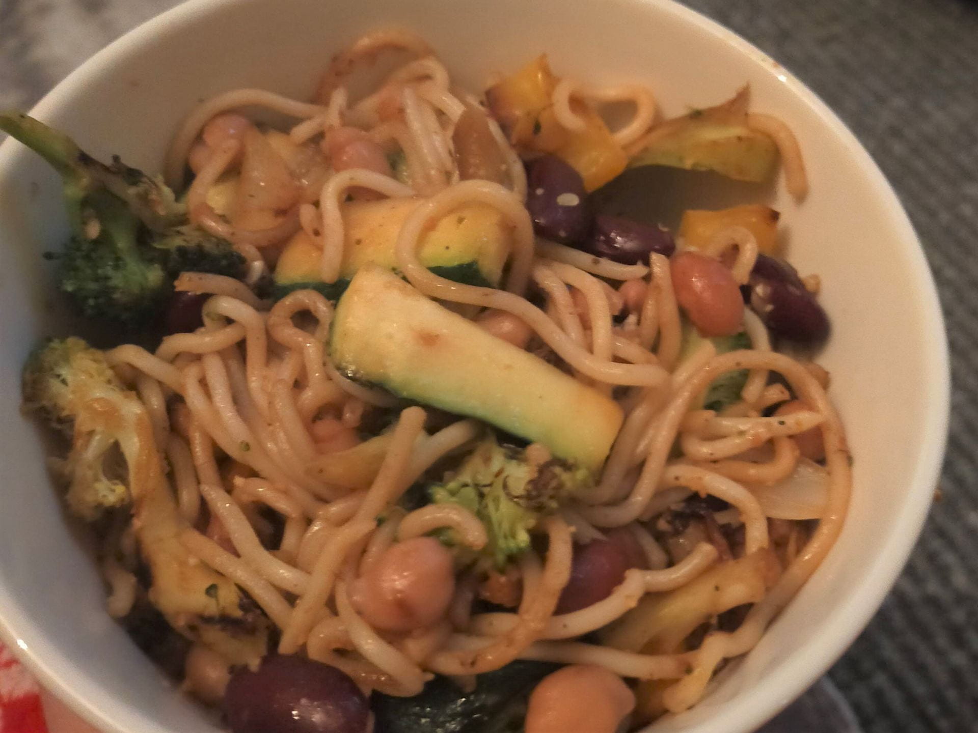 A noodle stir fry. There are noodles in a bowl with vegetables, including broccoli and courgette.