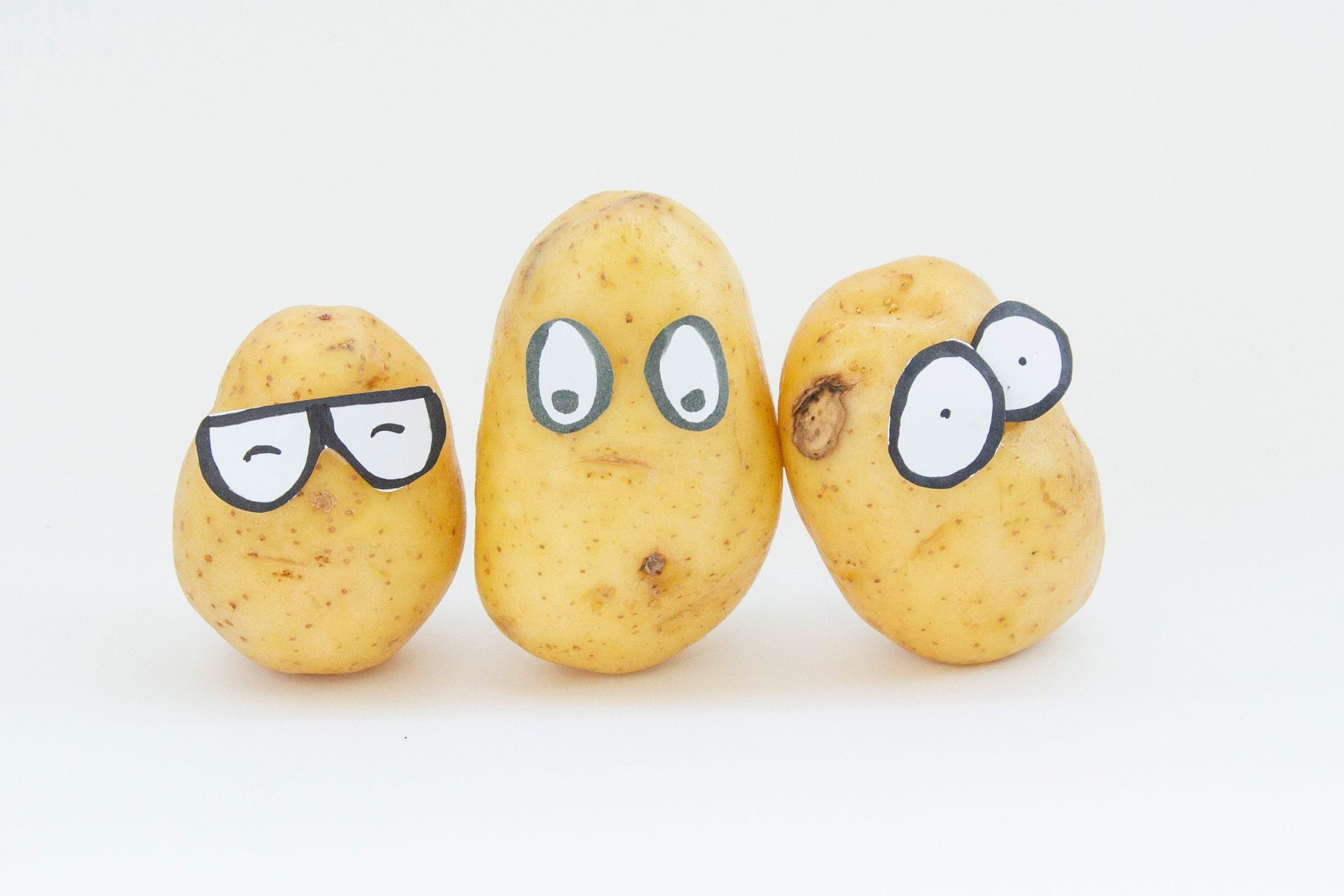 Three potatoes with cartoon eyes drawn onto paper stuck on them.