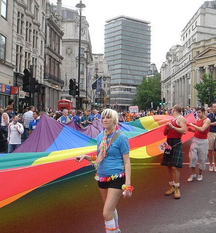 People at London Pride with hundreds of people holding one big pride flag
