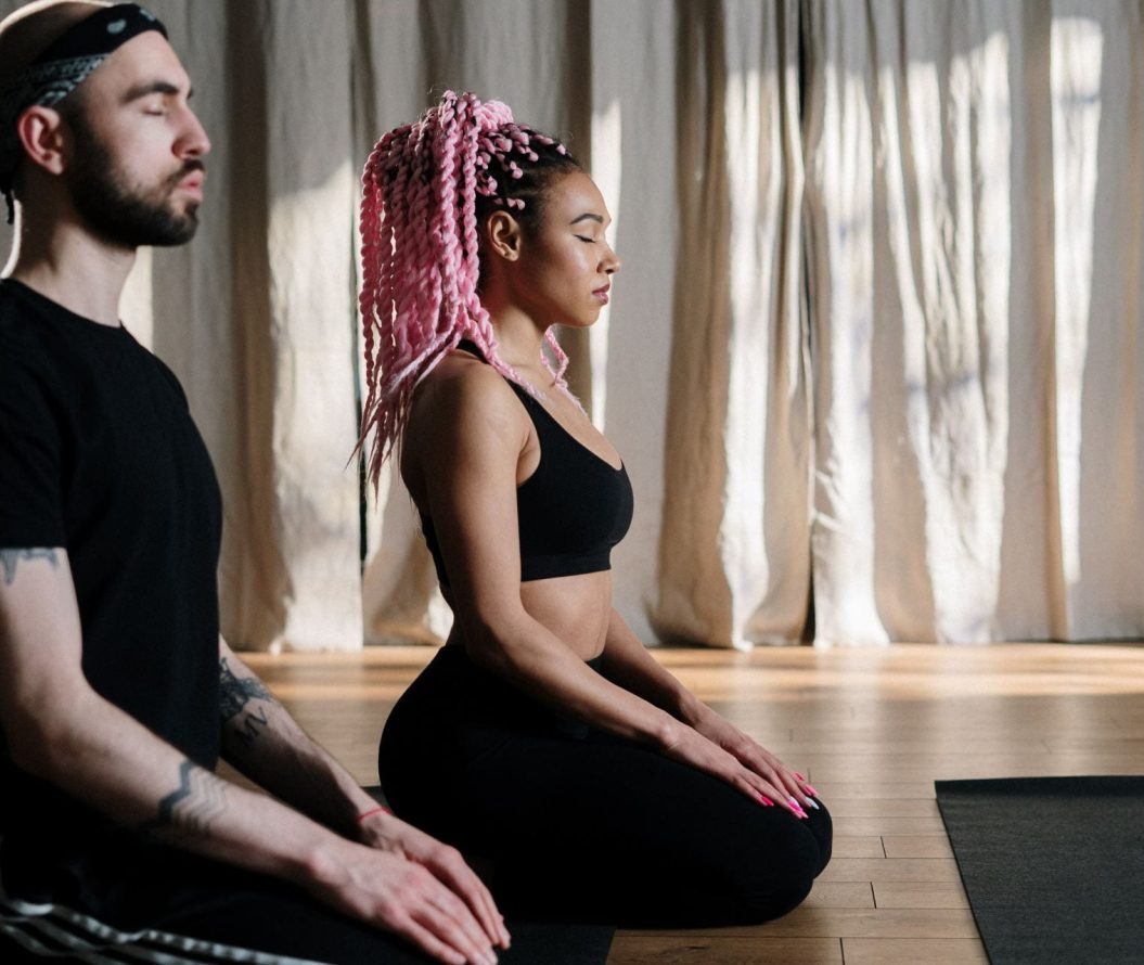 Two people sat performing meditation before yoga