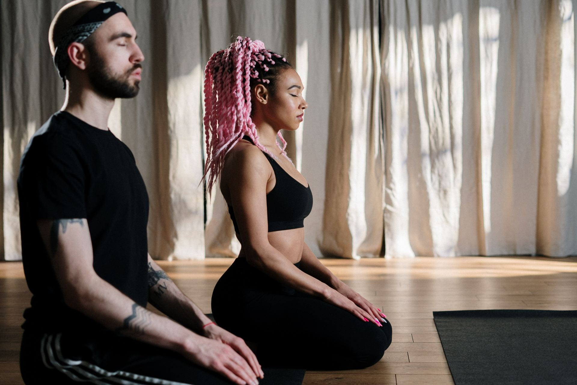 Two people sat performing meditation before yoga