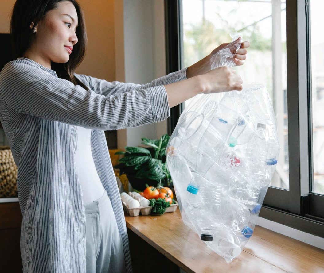 women holding bag of plastic bottles