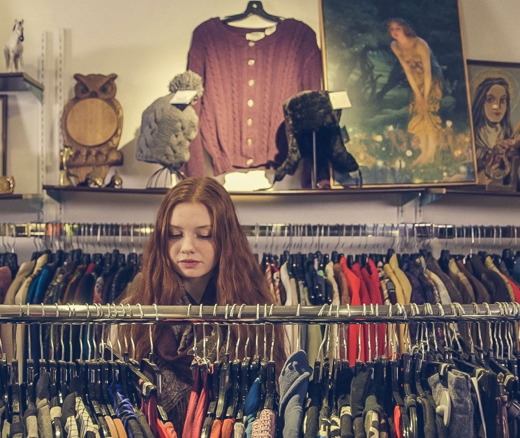 A woman browsing through a charity shop aisle