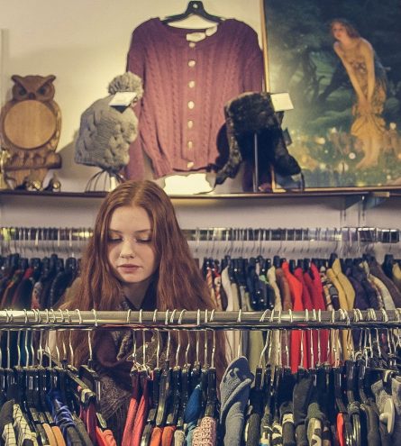 A woman browsing through a charity shop aisle