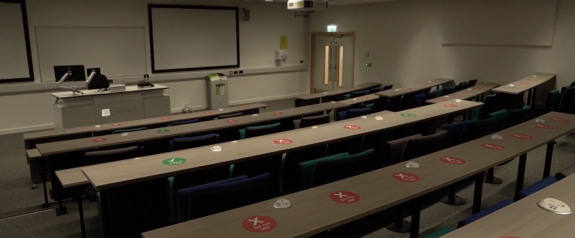 Medical building lecture hall. Shows rows of seating facing a blank projector screen. 